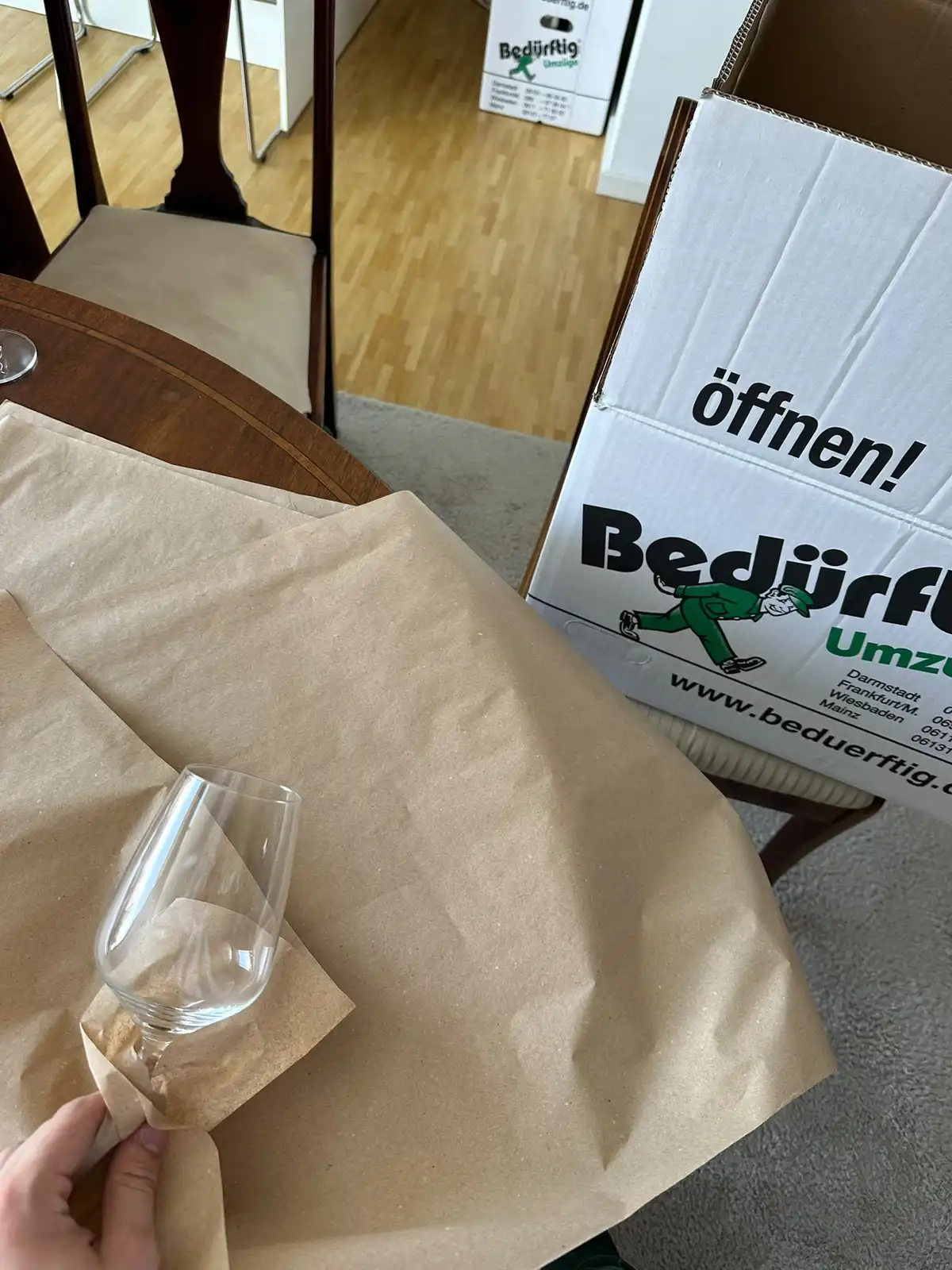 Weinglas wird für den Umzug einzeln in Packpapier eingeschlagen