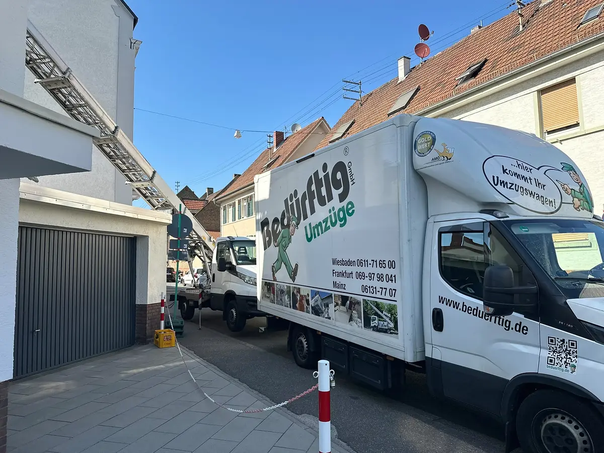 Umzugsfahrzeug der Bedürftig Umzüge GmbH mit Außenaufzug an einem Wohngebäude